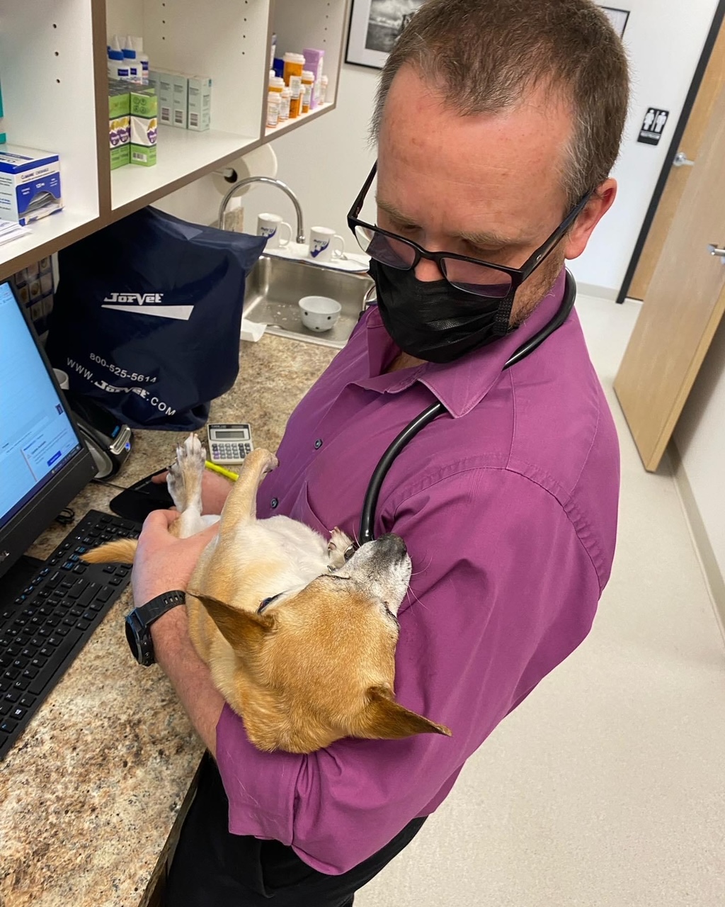 Dr. Landry loves his patients - holding a dog